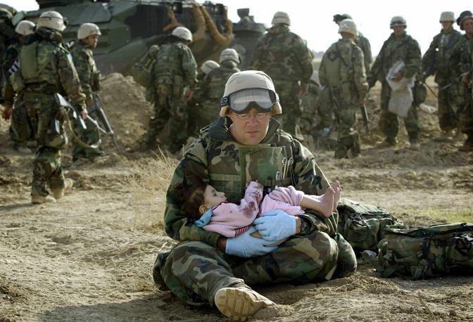 Marzo 2003: un marine americano tiene in braccio un bambino iracheno in una zona centrale del Paese dopo uno scontro a fuoco che ha coinvolto dei civili (Damir Sagolj/Reuters)