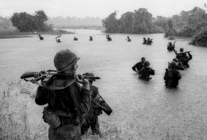 Paratroopers of the U.S. 2nd Battalion, 173rd Airborne Brigade hold their automatic weapons above water as they cross a river in the rain during a search for Viet Cong positions in the jungle area of Ben Cat, South Vietnam on Sept. 25, 1965. (AP Photo/Henri Huet)