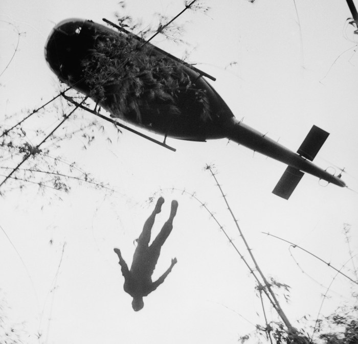 The body of an American paratrooper killed in action in the jungle near the Cambodian border is raised up to an evacuation helicopter in War Zone C, Vietnam in 1966. (AP Photo/Henri Huet)
