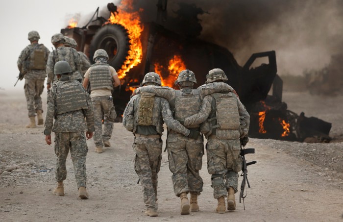 A soldier with an injured ankle from the US Army's 1-320 Field Artillery Regiment, 101st Airborne Division is assisted past his burning M-ATV armored vehicle after it struck an Improvised Explosive Device (IED) on a road near Combat Outpost Nolen in the Arghandab Valley in this picture taken July 23, 2010. None of the four soldiers in the vehicle were seriously injured in the explosion. (REUTERS/Bob Strong)