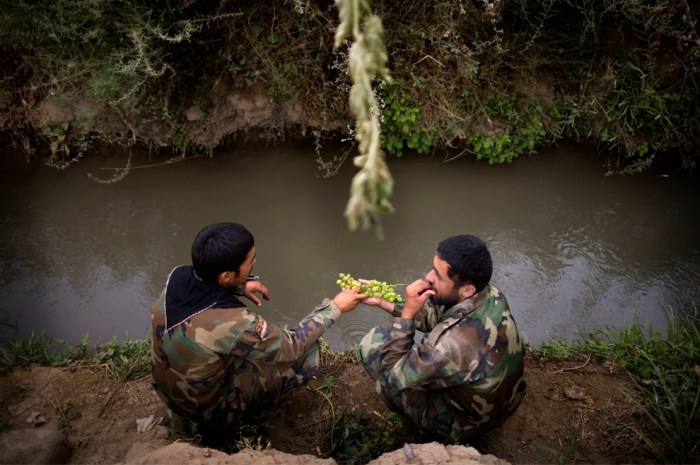 Afghan army soldiers share grapes beside a small canal after arriving to reinforce U.S. troops at Combat Outpost Nolen, in Arghandab Valley, in Kandahar, Afghanistan, Thursday, July 22, 2010. (AP Photo/Rodrigo Abd)