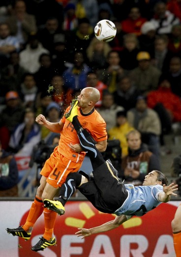 Sports: 1st prize singles. Mike Hutchings, South Africa, Reuters. Netherlands Demy de Zeeuw is kicked in the face by Uruguay's Martin. Cáceres during World Cup semi-final, Cape Town, 6 July Sports: 1st prize singles. Mike Hutchings, South Africa, Reuters. Netherlands Demy de Zeeuw is kicked in the face by Uruguay's Martin. Cáceres during World Cup semi-final, Cape Town, 6 July